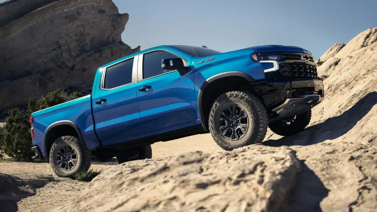 A blue Chevy Silverado 1500 driving over rocky terrain