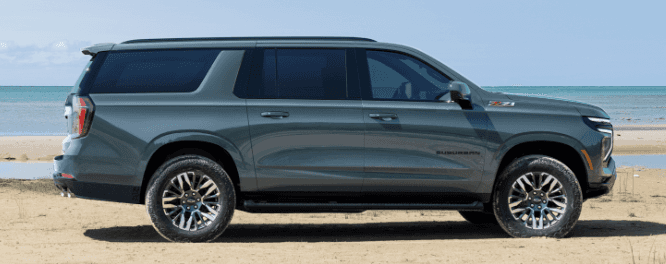 A turquoise Chevrolet Suburban in profile on a beach