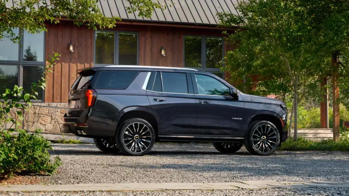 A blue Chevrolet Tahoe in profile parked by a cabin
