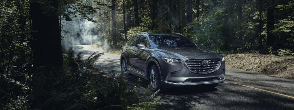 Certified Pre-Owned Mazda CX-9 SUV driving through a forest landscape