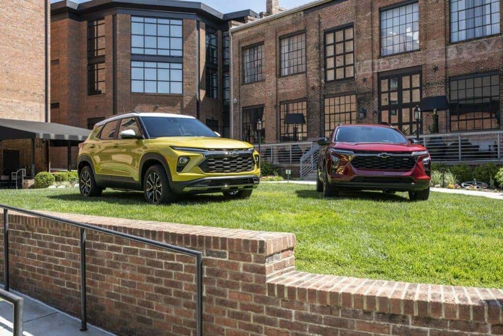 View of 2024 Chevrolet Trax RS in Crimson Red Metallic and 2024 Chevrolet Trailblazer LT in in Nitro Yellow Metallic staged in front of the Foundry Hotel Asheville.