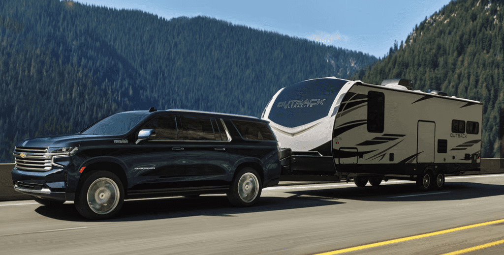 Chevrolet Suburban Towing a Camper on a Mountain Highway 3/4 View