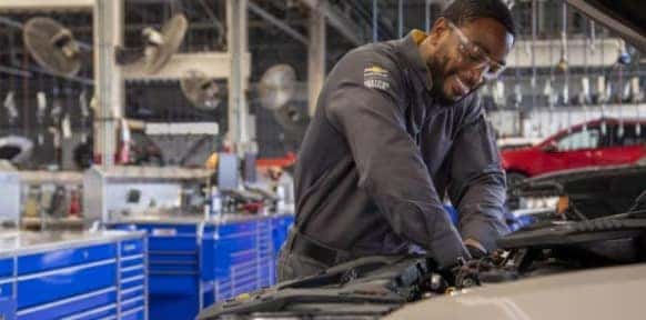 Certified Chevrolet technicians working in a service bay, performing maintenance with OEM tools and parts