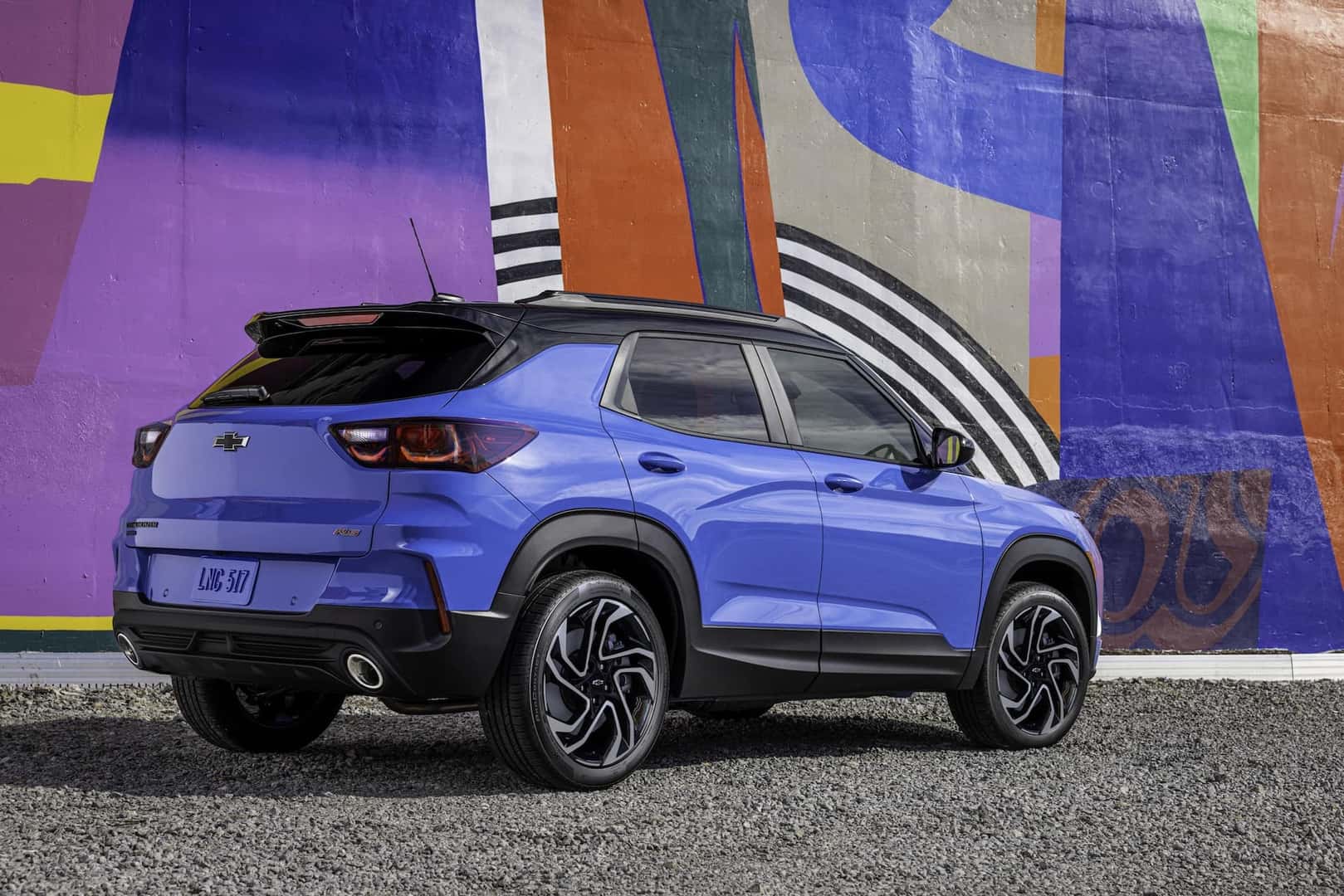 Rear 3/4 view of 2024 Chevrolet Trailblazer RS in Fountain Blue driving past a building. Preproduction model shown. Actual production model may vary. Available in fall 2023.