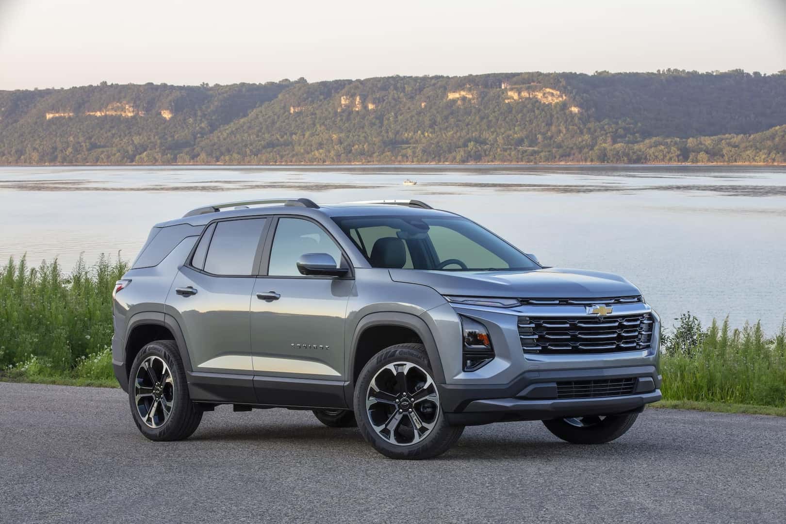 Front 3/4 view of a 2025 Chevrolet Equinox LT in Sterling Gray Metallic parked near a large body of water.
