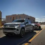 Chevrolet Silverado driving on the road towing an older Chevrolet