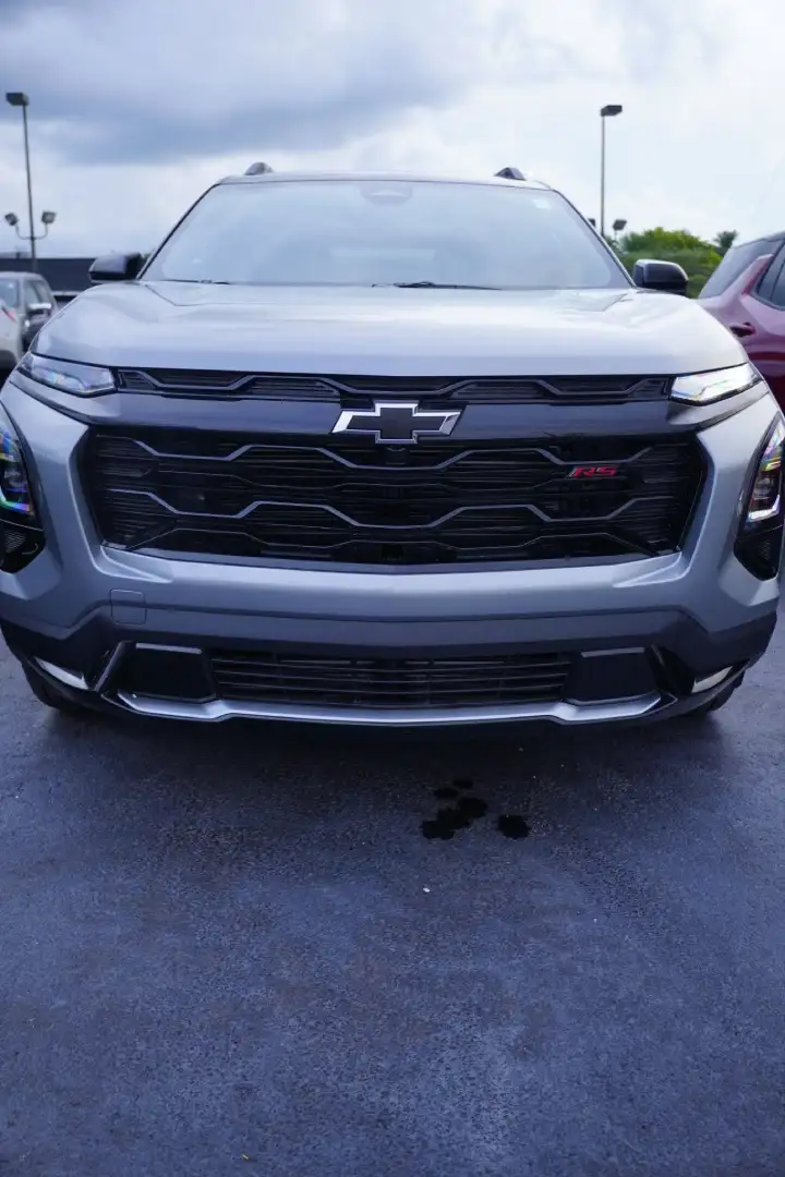 Direct front view of a silver Chevrolet Equinox RS crossover, featuring a black mesh grille, black bowtie emblem, red RS badging, and sleek modern LED headlights