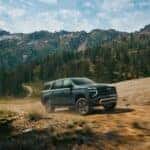 The Spacious And Family Friendly 2026 Chevrolet Suburban Kicking Up Dust As It Races On Dirt Roads Near A Vast Forests