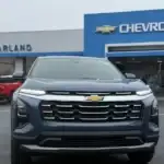 Straight-on front view of a blue Chevrolet Equinox compact SUV parked directly in front of the McFarland Chevrolet dealership entrance in Maysville, KY