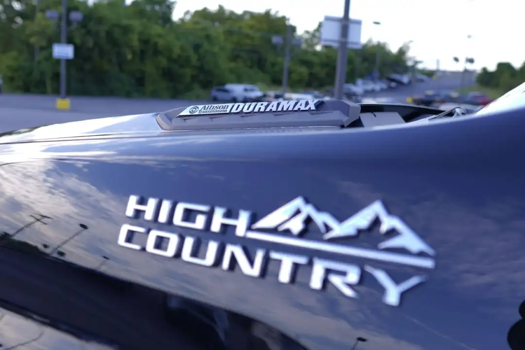 Close-up of the chrome High Country emblem on a black Chevrolet Silverado truck, highlighting the Allison Transmission and Duramax badge on the hood scoop at McFarland Chevrolet