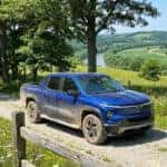 2026 Chevrolet Silverado EV on a gravel lane near a rural Kentucky nature preserve with hardwood trees and rolling hills