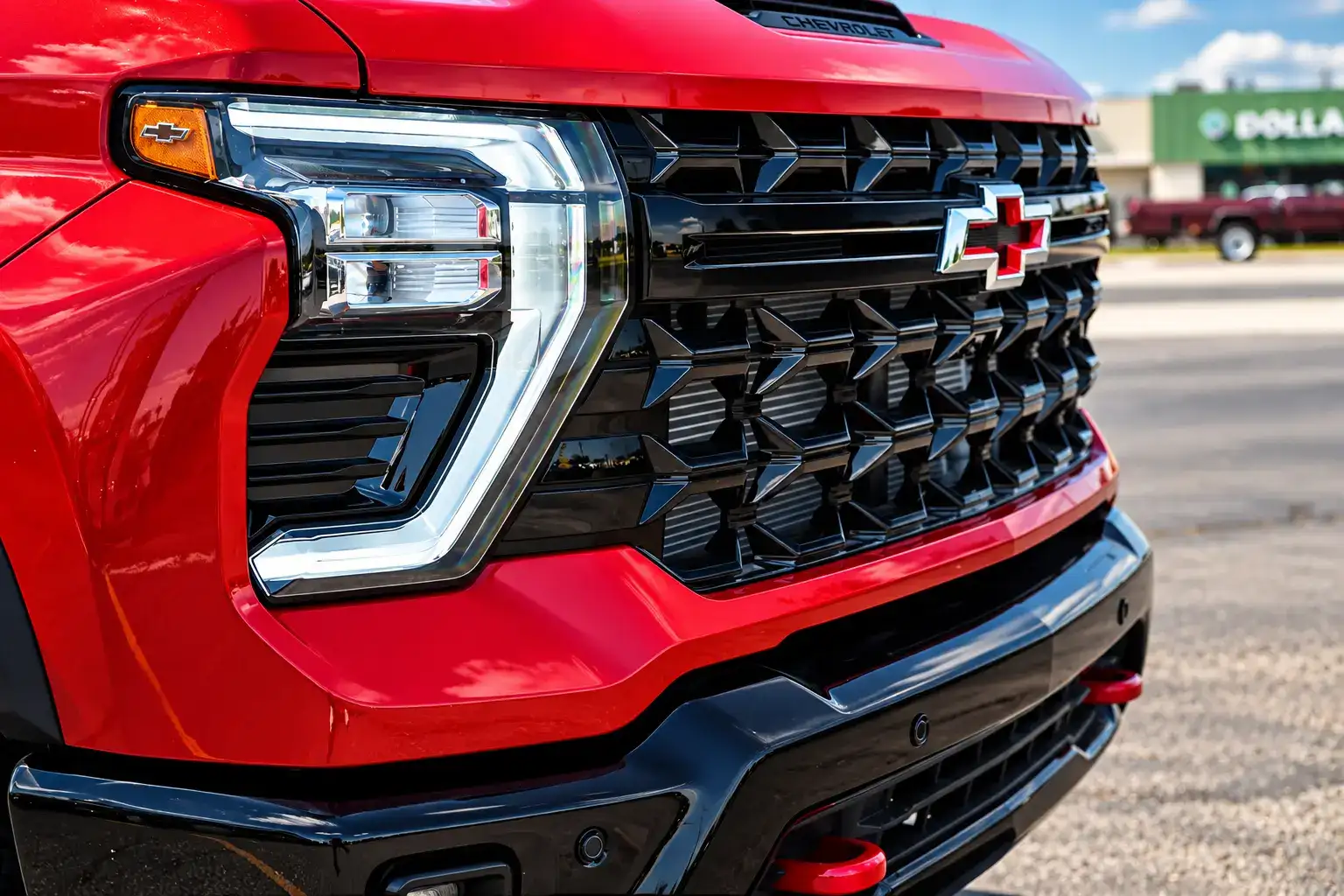 Close-up of a Chevrolet Silverado 2500HD featuring a black front grille, red Chevrolet bowtie emblem, LED headlights, and front bumper.