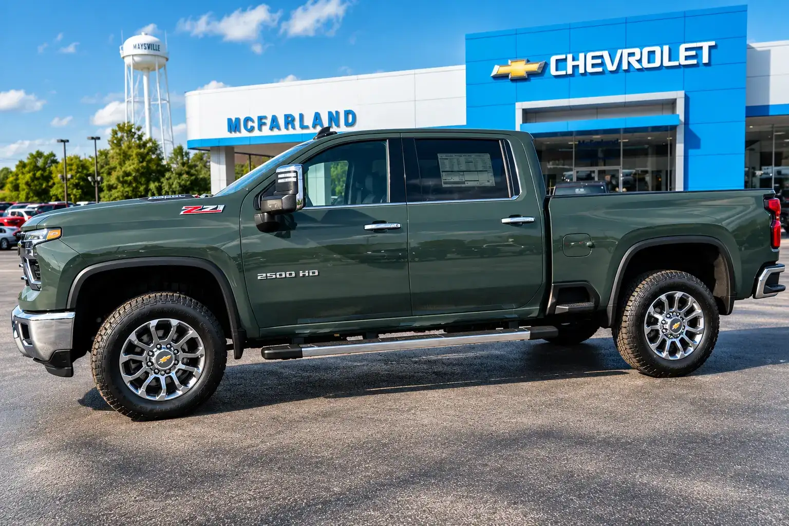 Dark green Chevrolet Silverado 2500HD Z71 Crew Cab with chrome wheels parked outside McFarland Chevrolet dealership.