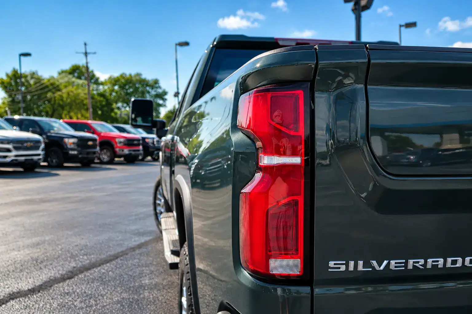 Close-up of a Chevrolet Silverado RST featuring a red LED taillight, glossy black tailgate, and chrome Silverado badging.