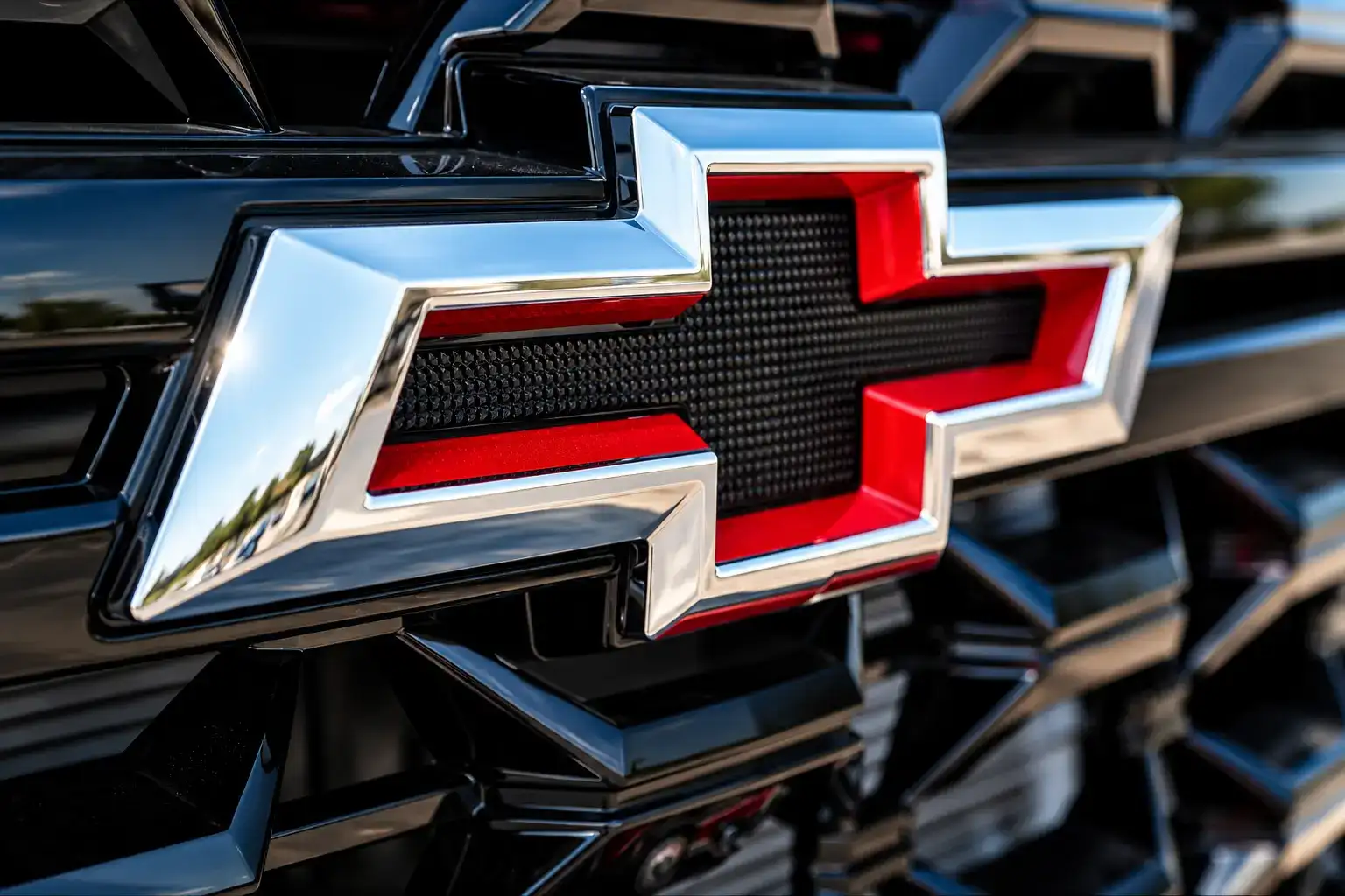 Close-up of the Chevrolet Silverado front grille featuring a red and chrome Chevrolet bowtie emblem against a black textured grille.