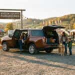 2026 Chevrolet Suburban at a Kentucky county fairgrounds entrance with families unloading, autumn afternoon light