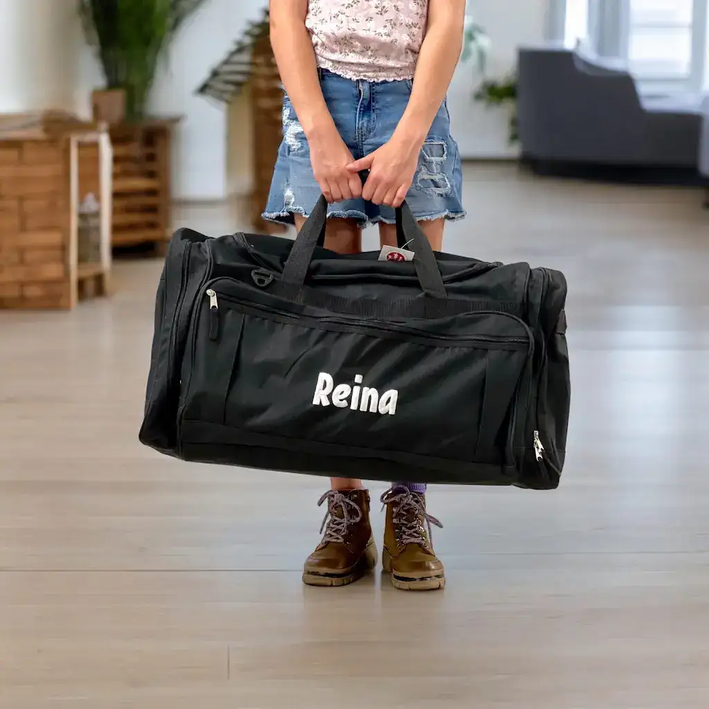 Young girl smiling as she holds a Bag of Hope duffel bag