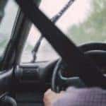 Person behind the steering wheel of a car driving in the rain
