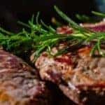 Two pieces of steak served with a garnish