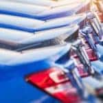 A line of blue and black cars are shown from their trunks at a dealership for used cars near me.