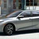 A silver 2019 Honda Civic, which is popular among used cars in Philadelphia, PA, is backing into a parking spot on the street.