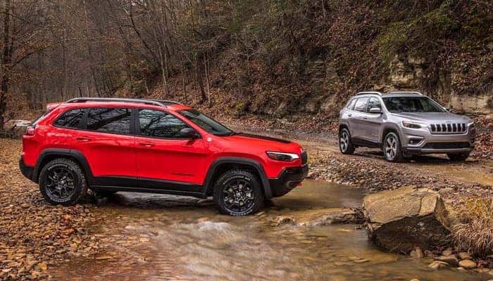 Red 2019 Jeep Cherokee Trailhawk and Silver 2019 Jeep Cherokee Limited at creek