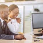 happy couple signing papers with salesman at dealership