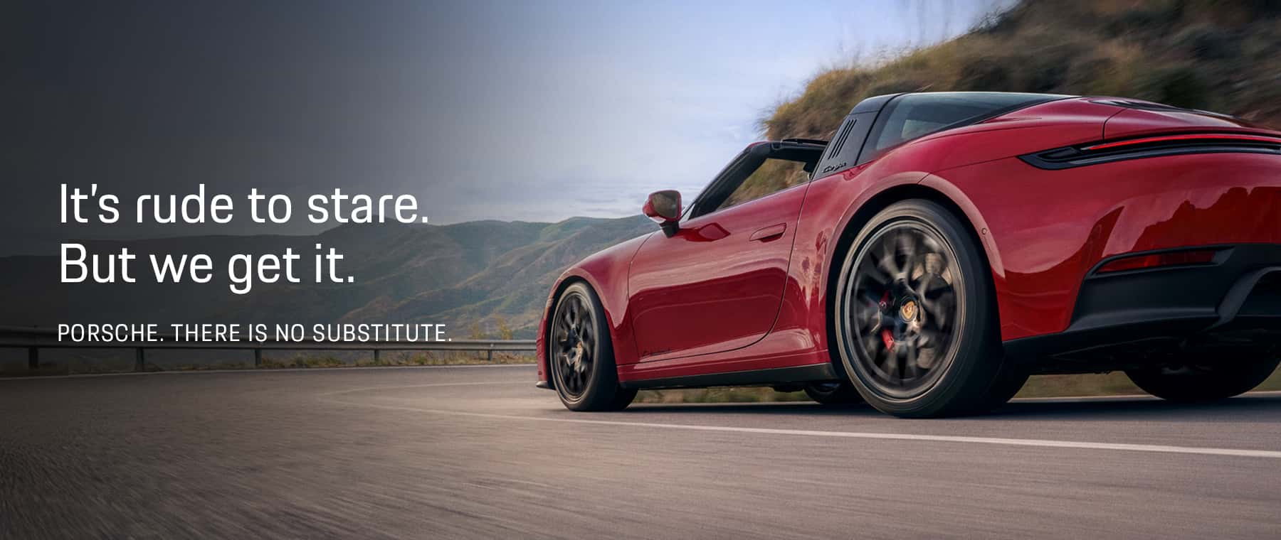 It's rude to stare. But we get it. Porsche. There is no substitute. Image of red 911 Targa driving on windy road.