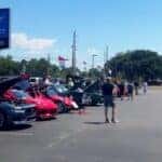 An image displaying the front of Preston Hood Chevrolet dealership with various cars displayed and people looking at them.