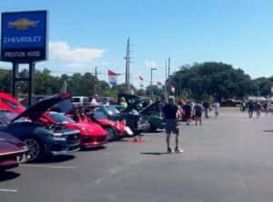 An image displaying the front of Preston Hood Chevrolet dealership with various cars displayed and people looking at them.