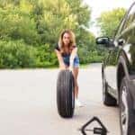 Woman changing tire on a road