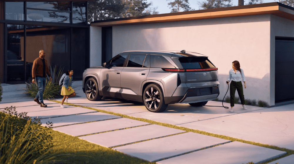 Gray 2027 Toyota Highlander parked in a driveway with a family