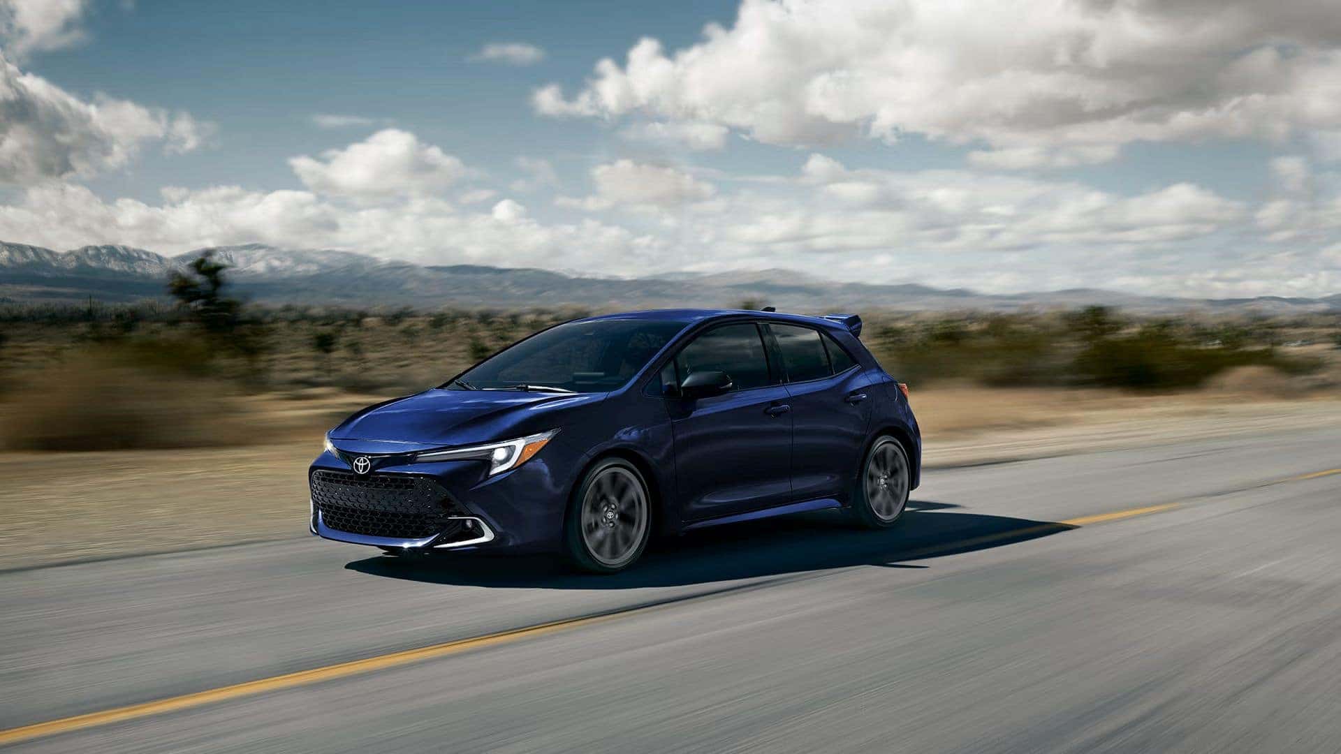 Navy Blue 2027 Toyota Corolla Hatchback driving on desert hightway