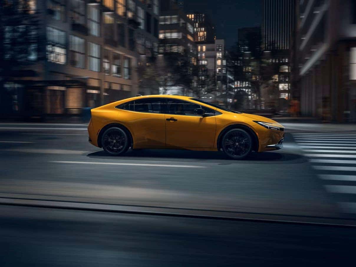 Yellow 2027 Toyota Prius driving through city intersection with heavy motion blur