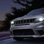 Silver 2018 Jeep Grand Cherokee driving through a starry night