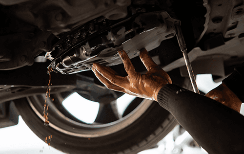 Service technician draining transmission fluid.