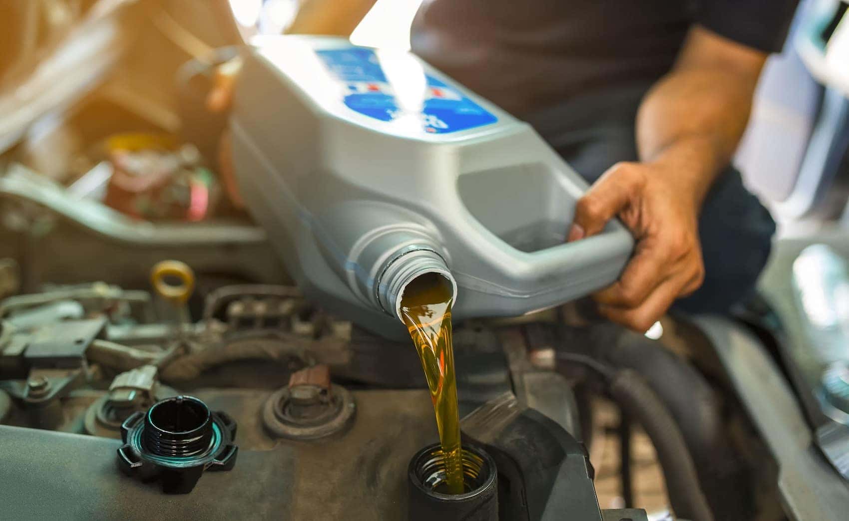 Car mechanic replacing engine oil