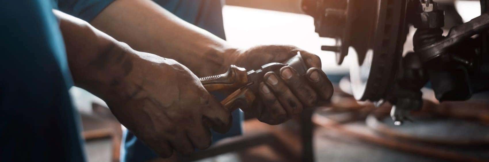 mechanics hands holding tool next to disc rotor