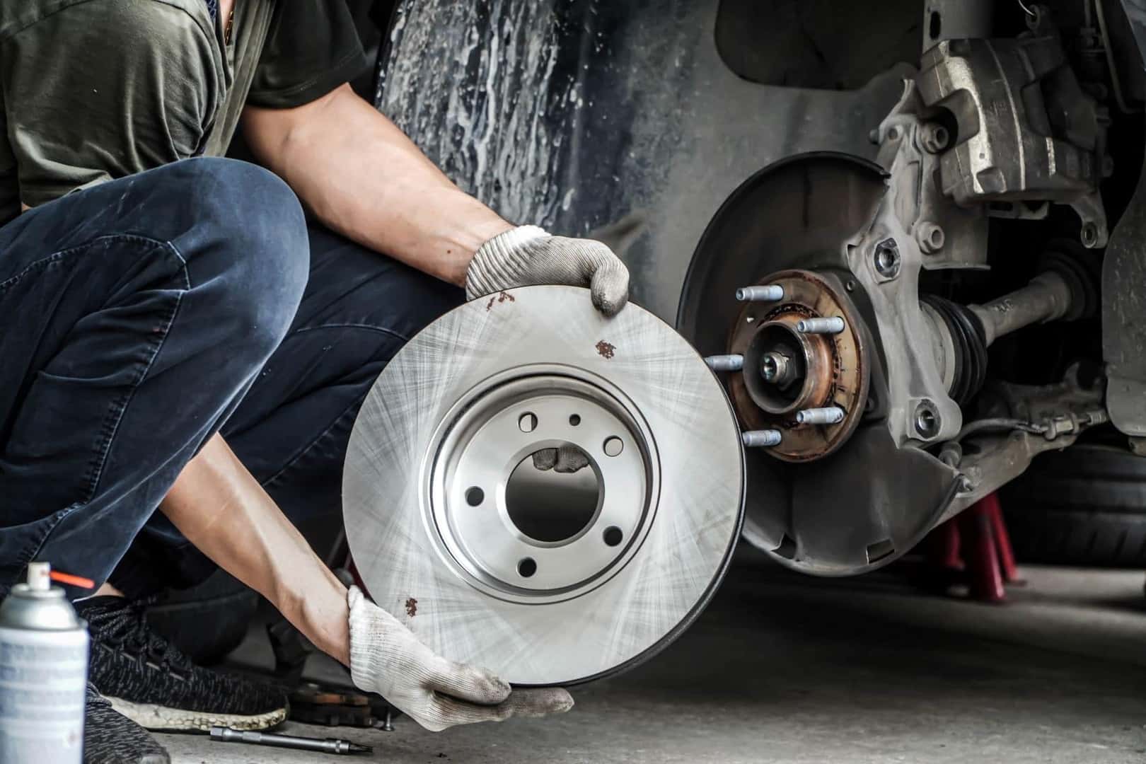 Technician holding Disc Rotor next to vehicle