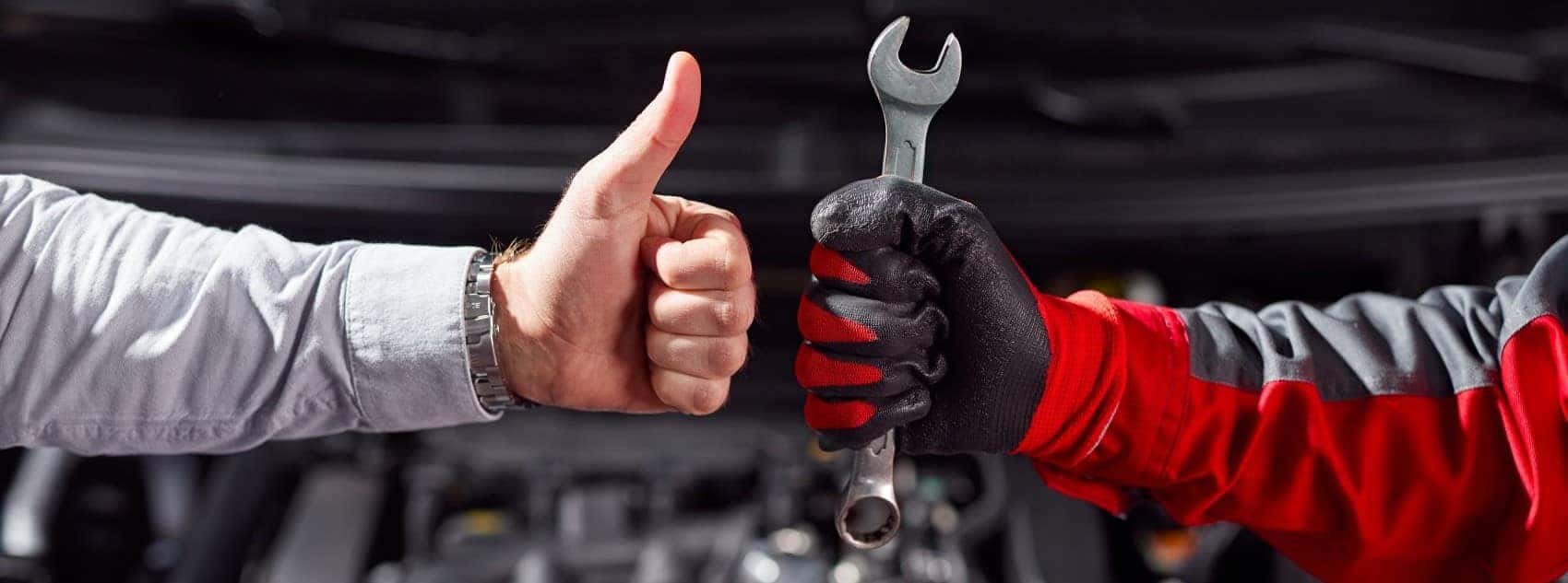 Driver giving a thumbs up while a mechanic holds a wrench